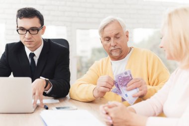 Olgun çift bir avukat ile bir resepsiyonda. Avukat çalışıyor. Yaşlı insanlar yan yana oturmak ve para göz önünde bulundurun. Onlar avukatın ofisinde masada oturuyorlar.