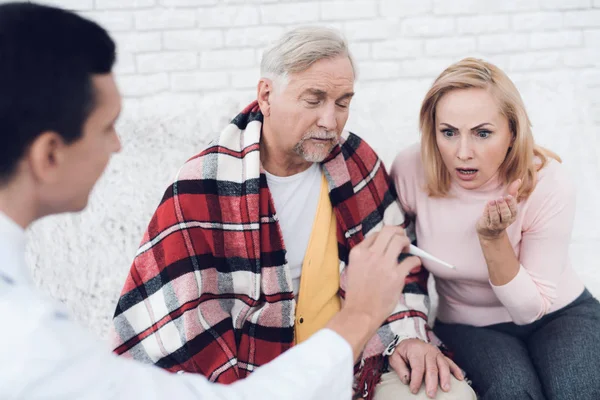 一位医生穿着一件黄色的羊毛衫来到老人面前 医生给她看了体温计 女子很震惊 他们在一对年迈的夫妇的房子里 — 图库照片