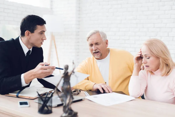 A couple of old people came to see a realtor. The old man and the woman are very upset. The realtor calm explains what is written in the documents. They are in the office of a realtor.