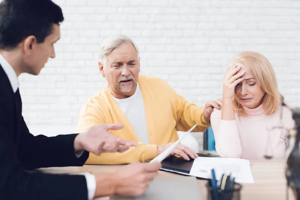 A couple of old people came to see a realtor. The old man and the woman are very upset. The realtor calm explains what is written in the documents. They are in the office of a realtor.
