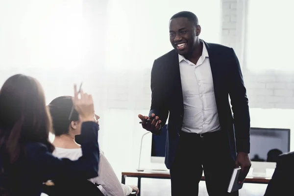 A black man talks to employees of a business office at a seminar. — Stock Photo, Image