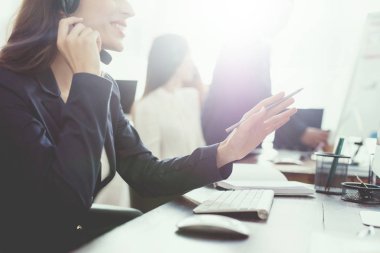Genç bir kız ofiste bilgisayar ekranında arıyor ve telefonda konuşuyor.