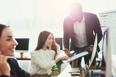 Kadın bir işleç ve bir siyah adam onların ofisinde bir şey görüşüyorlar.