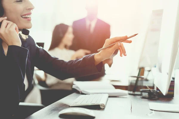 Ein junges Mädchen blickt im Büro auf einen Computerbildschirm und telefoniert. — Stockfoto