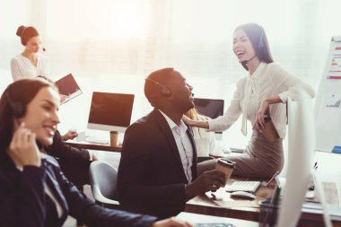 Çinli bir kız çağrı merkezi masada oturan ve siyah bir adamla konuşuyor.