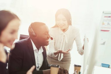 Bir kız onun meslektaşım çağrı merkezinde bir şey bilgisayar ekranında gösterir.