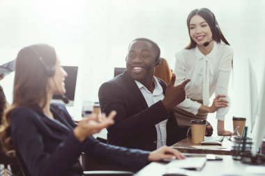 Çağrı merkezi operatörleri siyah bir adamla konuşmak gibi çalışan iki kız.