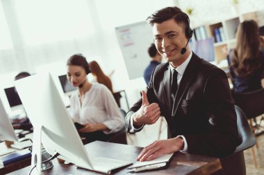 Adam çağrı merkezi kamera poz. Müşteriler için bir mikrofon aracılığıyla konuşuyor. O gülümsüyor.