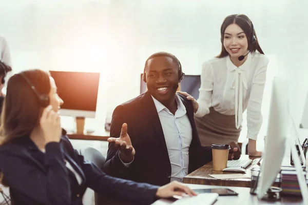 Two girls who work as operators in the call center talk to a black guy. — Stock Photo, Image