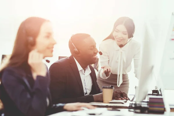 Ein Mädchen zeigt ihrem Kollegen im Callcenter etwas auf dem Computerbildschirm. — Stockfoto