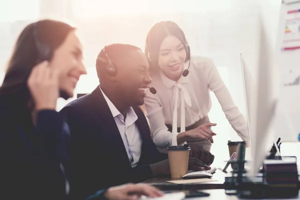 Ein Mädchen zeigt ihrem Kollegen im Callcenter etwas auf dem Computerbildschirm. — Stockfoto