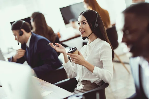 The Asian girl answers questions from clients in the call center. — Stock Photo, Image