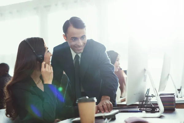 A man with a woman talking to each other in the office. They are both operators of the call center. They are in a good mood.