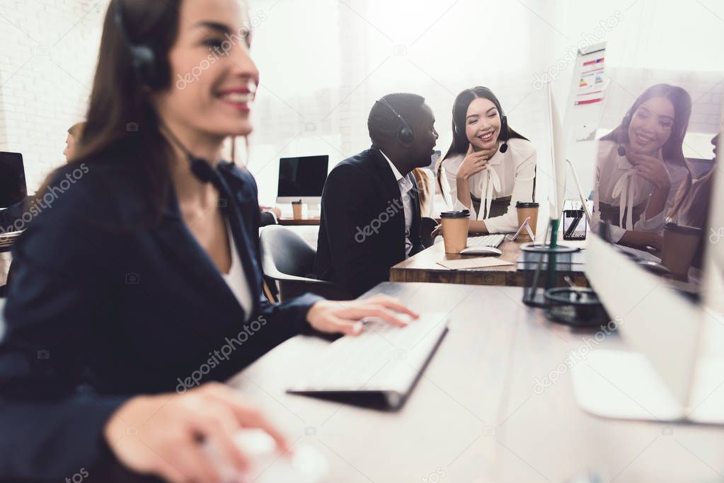 Two girls who work as operators in the call center talk to a black guy. They are in a good mood.