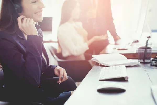 Ein junges Mädchen blickt im Büro auf einen Computerbildschirm und telefoniert. — Stockfoto