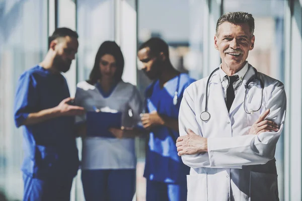 Porträtt leende mogen manlig läkare står med armarna korsade — Stockfoto