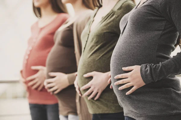 Zijaanzicht van drie zwangere vrouwen zijn hun buiken met handen aan te raken. Moederschap concept — Stockfoto