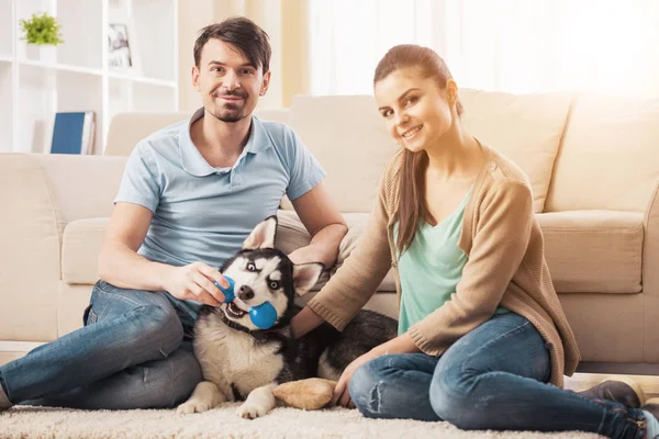 Casal jovem está brincando com seu cachorro Husky — Fotografia de Stock