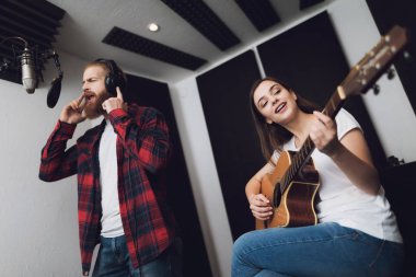 Bir erkek ve bir kadın bir kayıt stüdyosu bir şarkı söyle. Bir adam şarkı söylüyor ve bir kadın gitar çalıyor.