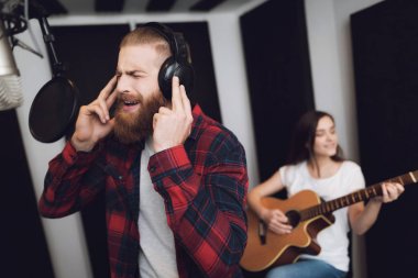 Bir erkek ve bir kadın bir kayıt stüdyosu bir şarkı söyle. Bir adam şarkı söylüyor ve bir kadın gitar çalıyor.