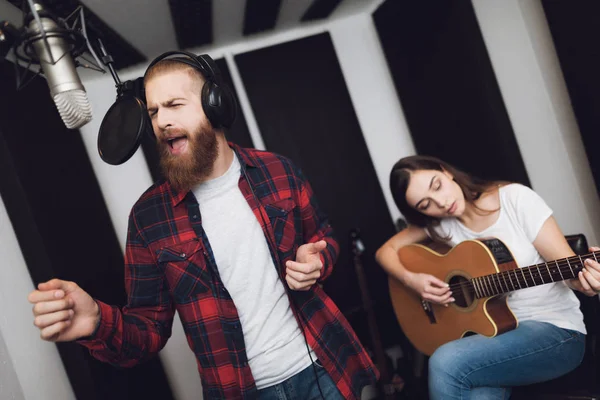 一个男人和一个女人在录音棚里唱一首歌 一个男人唱歌 一个女人弹吉他 — 图库照片