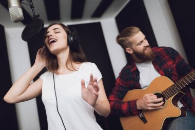 Bir kız ve bir adam bir modern kayıt stüdyosunda bir gitar için bir şarkı söyle. Kız şarkı söylüyor ve adam gitar çalıyor.