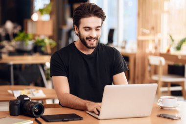 Serbest meslek sahibi adam masada oturan laptop yazarak sakallı.