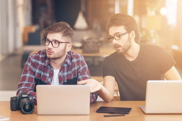 Dos hombres freelancer discutiendo en el portátil en el escritorio . — Foto de Stock