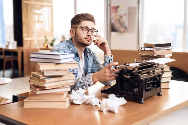 Freelancer man sprätta anteckningar på gamla typewritter sitter vid skrivbord. — Stockfoto