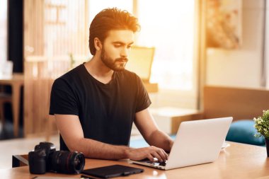 Serbest meslek sahibi adam masada oturan laptop yazarak sakallı.