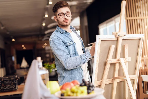 Freelancer homem pintura com escova de pé atrás cavalete . — Fotografia de Stock