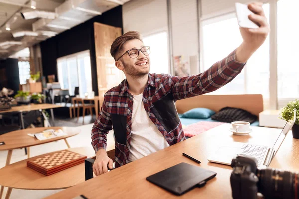 Freelancer człowiek biorąc selfie w laptopie siedząc przy biurku. — Zdjęcie stockowe