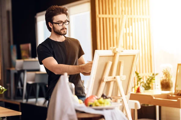 Freelancer hombre pintura con pincel de pie detrás del caballete . —  Fotos de Stock