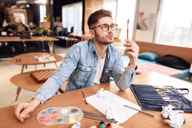 Serbest meslek sahibi adam masada oturma çizmek için fırça kullanma.