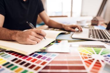 Serbest meslek sahibi adam masada oturan laptop notlar alarak sakallı.