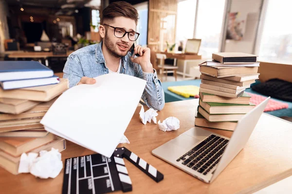 Freelancer mannen i telefon på laptop sitter vid skrivbord omges av böcker. — Stockfoto