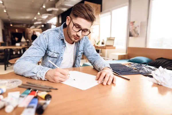 Freelancer man ritar på papper med penna som sitter vid skrivbord. — Stockfoto