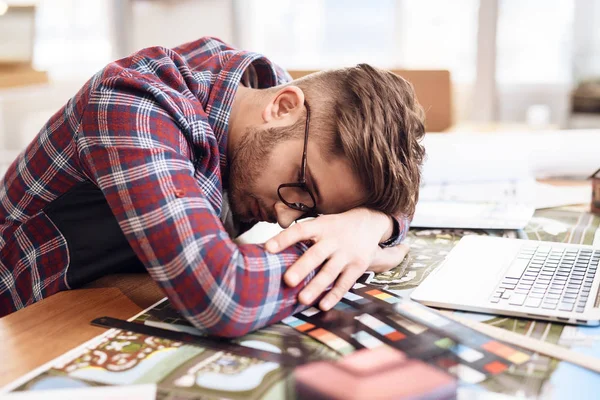 Na volné noze muž spí na notebooku sedí u stolu. — Stock fotografie