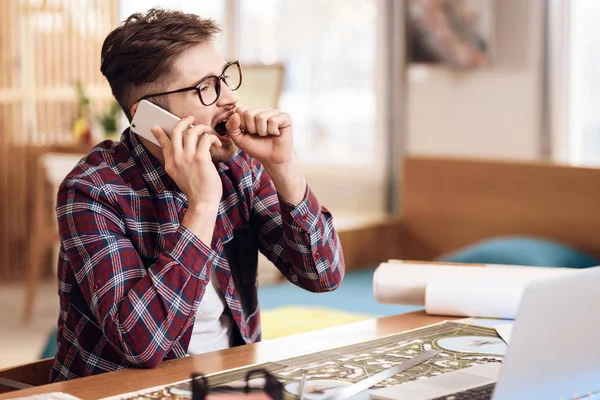 Freelancer człowiek rozmawia przez telefon o laptopie siedząc przy biurku. — Zdjęcie stockowe