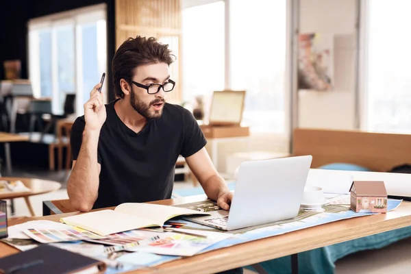 Freelancer bearded man tar anteckningar på laptop sitter vid skrivbord. — Stockfoto