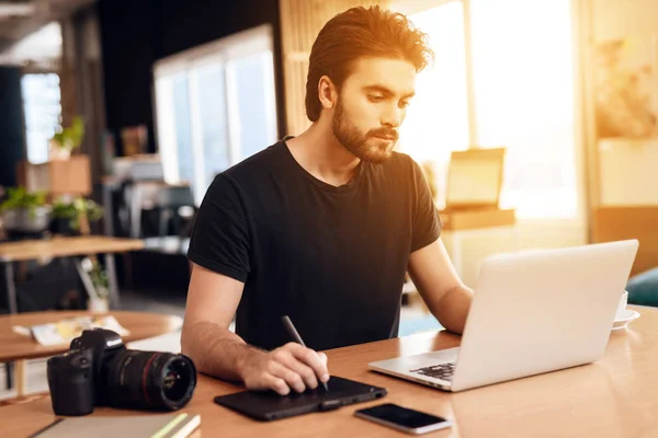 Freelancer barbudo hombre dibujo en el portátil sentado en el escritorio . — Foto de Stock