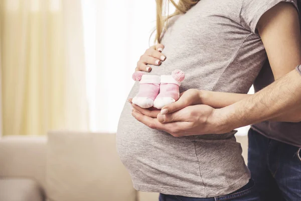 Man Zijn Zwangere Vrouw Proberen Baby Sokken Haar Buik Zijaanzicht — Stockfoto