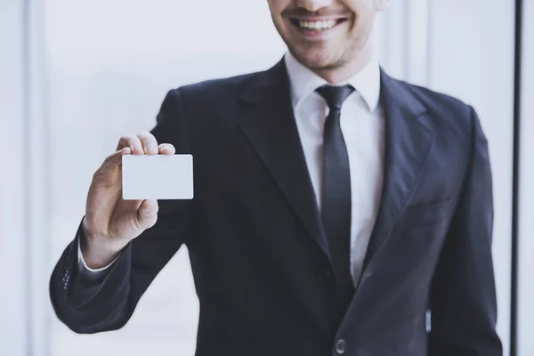 Sonriente hombre de negocios exitoso con tarjeta de visita o signo. En primer plano una tarjeta de visita —  Fotos de Stock