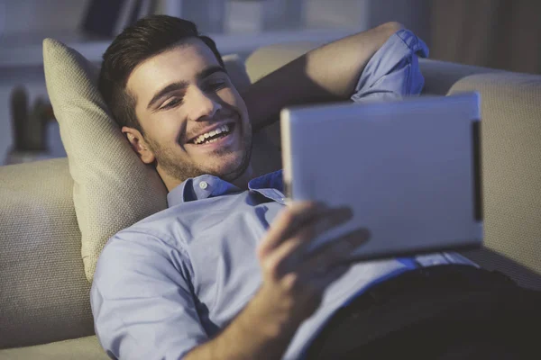 Χαμογελώντας όμορφος άντρας χρησιμοποιεί ψηφιακή δισκίο στο σπίτι — Φωτογραφία Αρχείου