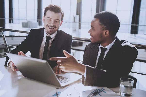 Deux jeunes hommes d'affaires travaillent avec un ordinateur portable dans un bureau moderne — Photo