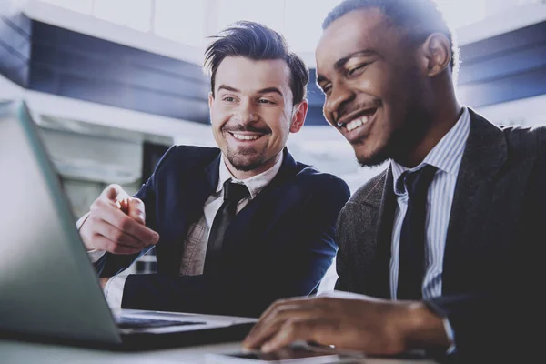 Deux jeunes hommes d'affaires travaillent avec un ordinateur portable dans un bureau moderne — Photo