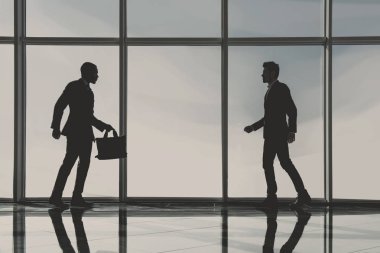 İki genç işadamları görünümünü siluet modern ofis panoramik pencereli bekliyoruz