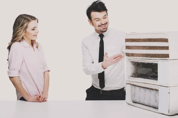 Smiling young man, salesman is showing a mattress made of coconut fiber — Stock Photo, Image