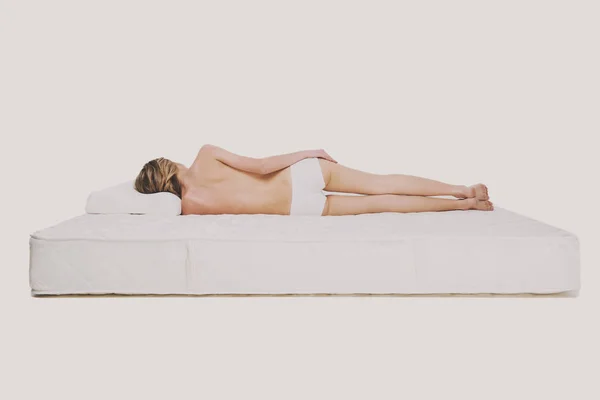 Vista posteriore della giovane donna è sdraiato su materasso di qualità — Foto Stock