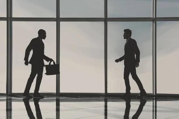 Silhouette view of two young businessmen are standing in modern office with panoramic windows — Stock Photo, Image